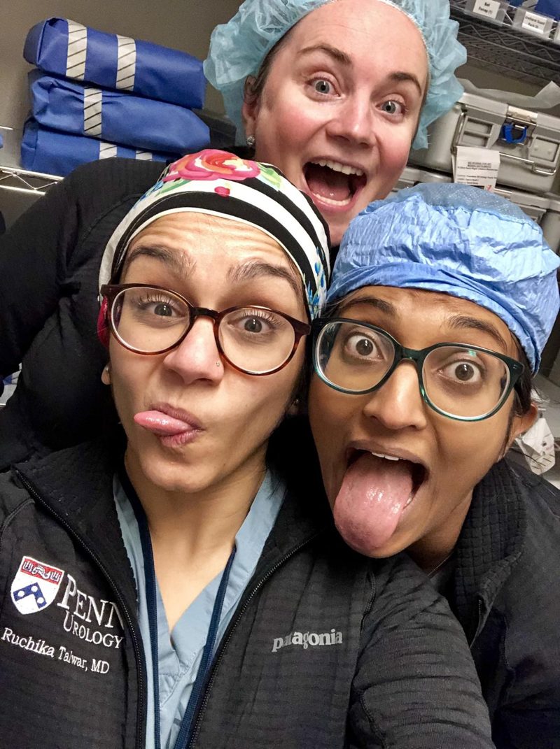 Three surgeons in scrub caps making silly faces for a selfie