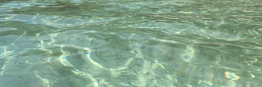 Clear turquoise water rippling over sand in the sun